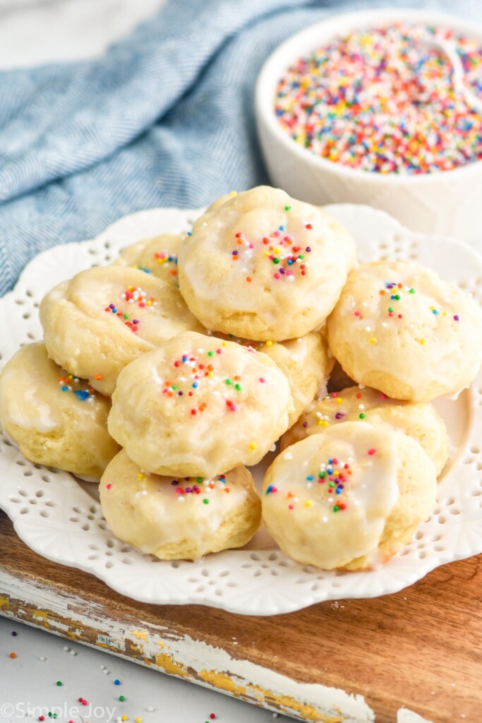 plate of ricotta cookies with bowl of sprinkles sitting beside