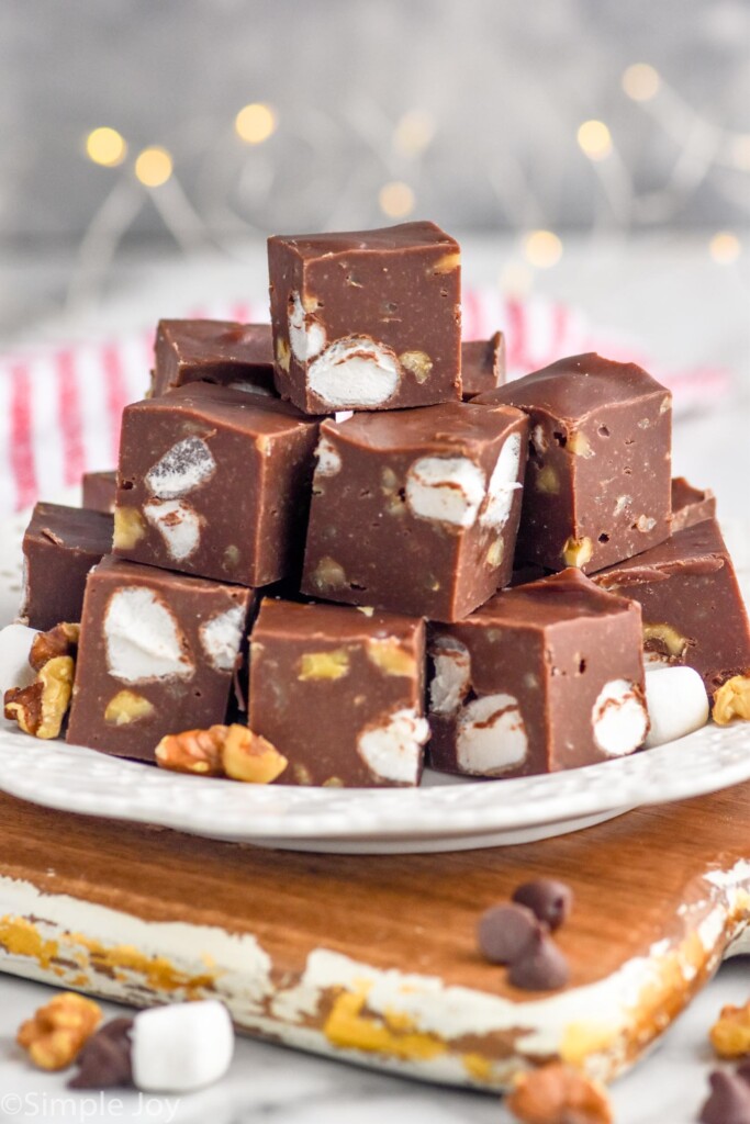 Side view of a plate of Rocky Road Fudge with nuts, marshmallows, and chocolate chips beside.
