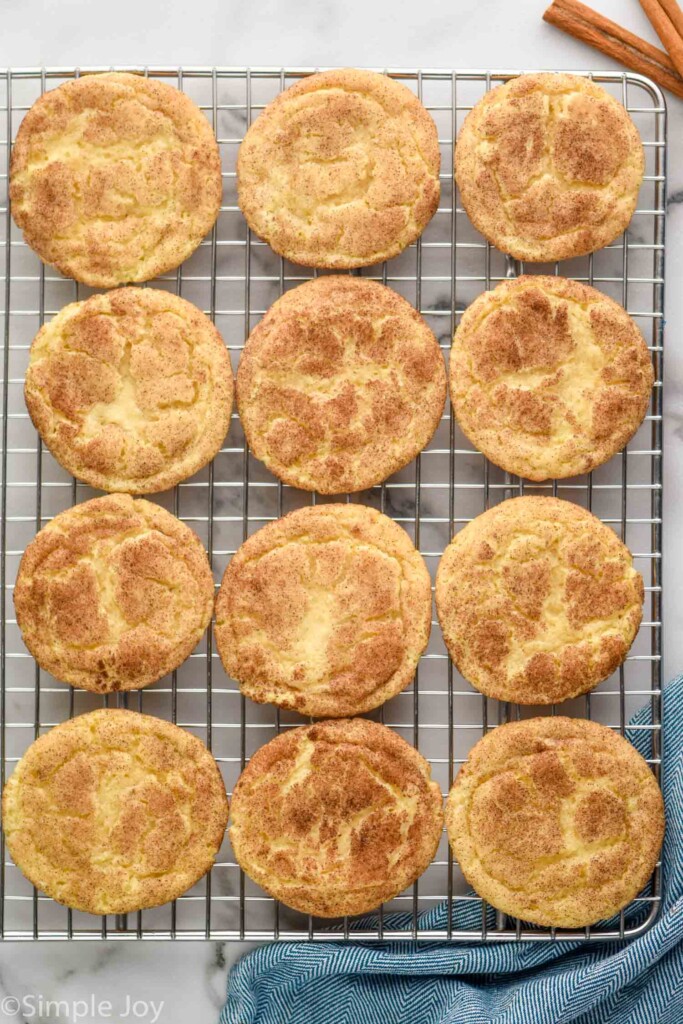 Overhead picture of Snickerdoodles on a baking sheet. Cinnamon sticks beside.