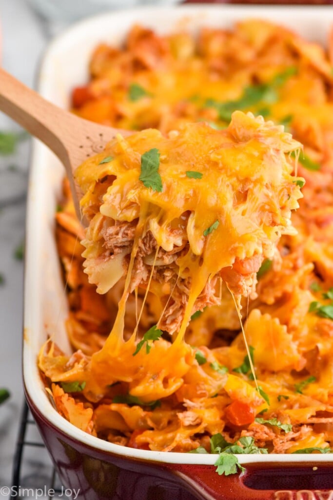 Close up photo of a spoon lifting a serving of Fajita Casserole out of baking dish of Fajita Casserole recipe.