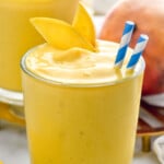 Mango Smoothie with straws and mango slice. Another Mango Smoothie and a mango beside. - 17