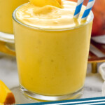 Pinterest graphic for Mango Smoothie recipe. Image shows Mango Smoothie with straws and mango slices, extra mango beside. Text says, "Mango Smoothie simplejoy.com"
