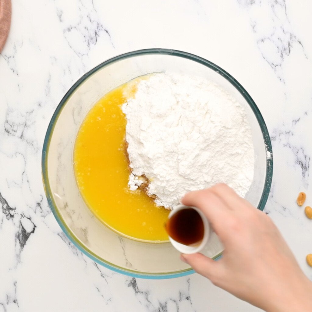 overhead of a bowl with powdered sugar and melted butter and vanilla being poured in