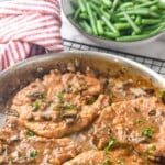 Pinterest graphic for Smothered Pork Chops. Text says "amazing Smothered Pork Chops simplejoy.com" Image shows a pan of Smothered Pork Chops with bowl of green beans in the background
