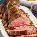beef tenderloin on a platter with potatoes and salad sitting in background - 14
