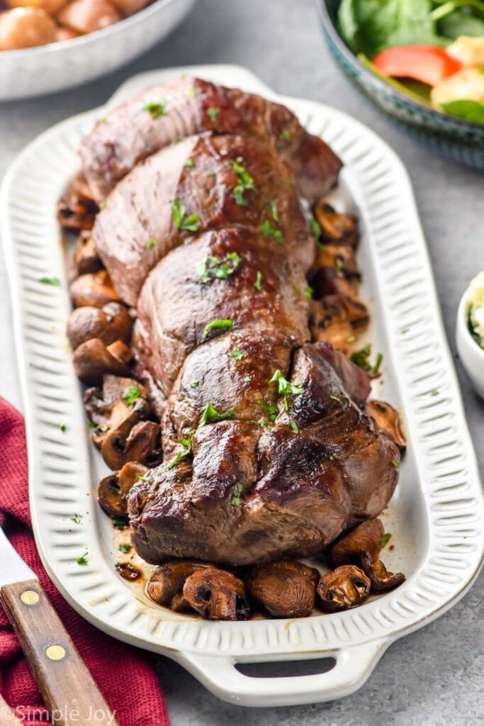 beef tenderloin on a platter with mushrooms