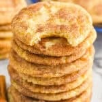 Stack of Snickerdoodles with a bite taken out of the top cookie. Cinnamon sticks beside.