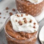 Two bowls of Chocolate Pudding garnished with whipped cream and chocolate shavings. Spoon beside. - 8