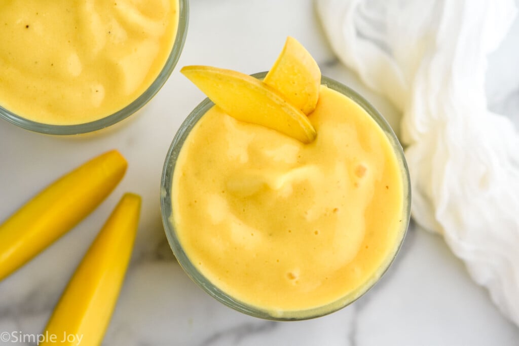 Overhead view of Mango Smoothie with mango slices. Mango slices and another smoothie beside.