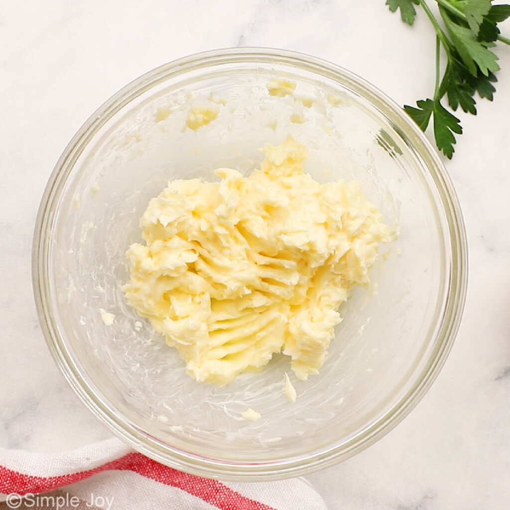 Overhead view of mixing bowl of butter preparing for garlic butter to garnish beef tenderloin. - 10