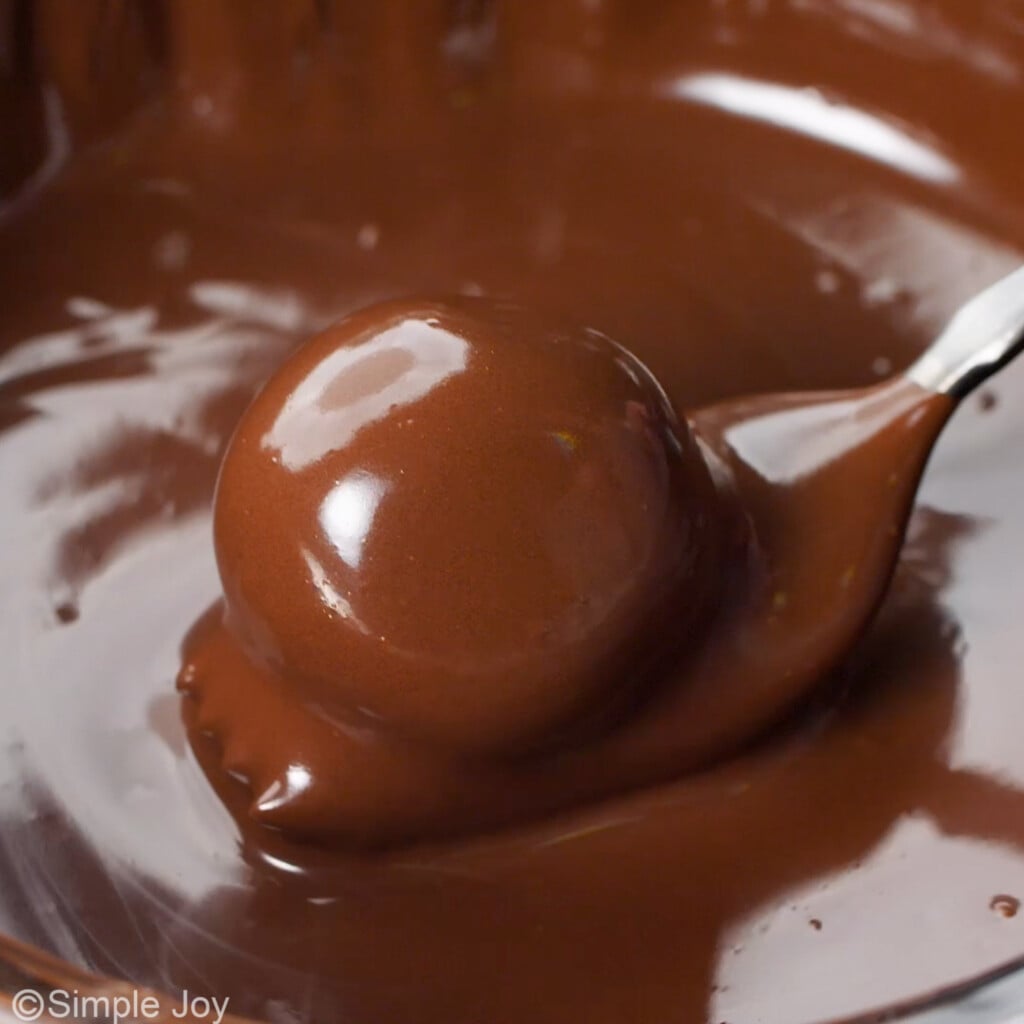 a chocolate coated peanut butter ball coming out of melted chocolate