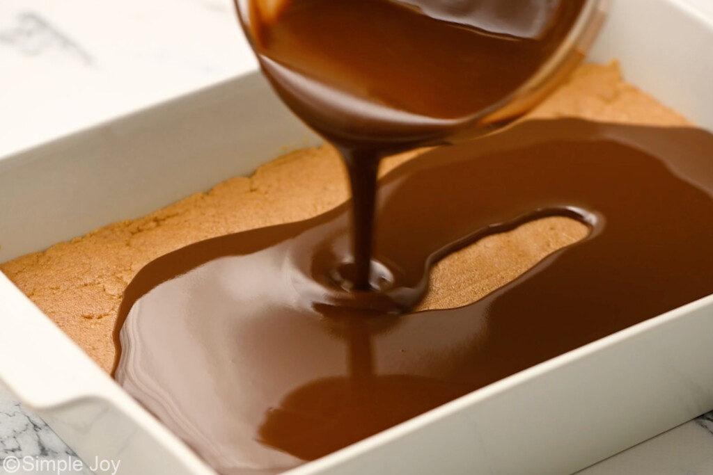 chocolate being poured over peanut butter bars