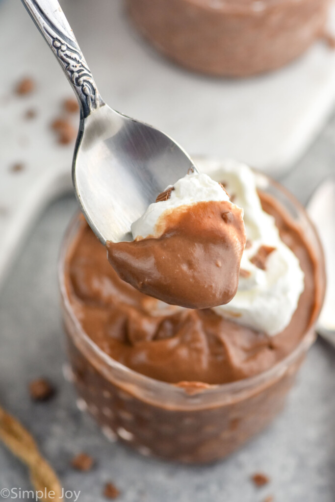 Close up photo of a spoonful of Chocolate Pudding over cup of Chocolate Pudding