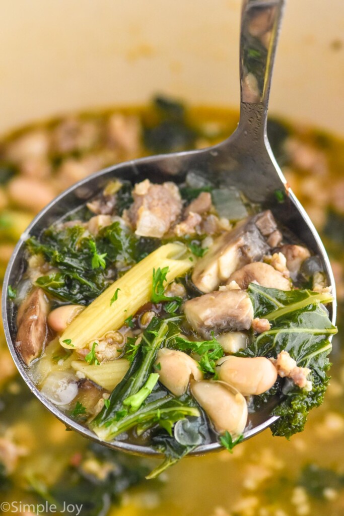 Close up photo of a ladle of sausage and kale soup