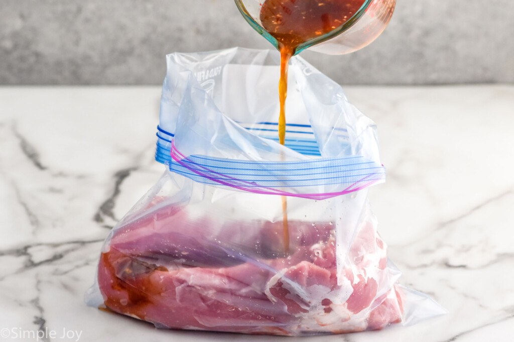 Side view of marinade being poured into a bag with pork tenderloin for Teriyaki Pork Tenderloin recipe.