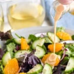 Pinterest graphic for ginger dressing. Text says "the best ginger dressing simplejoy.com" Image shows ginger dressing pouring onto bowl of salad.