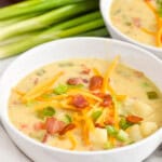 bowl of creamy potato soup with bacon topped with cheese, bacon, and scallions - 21