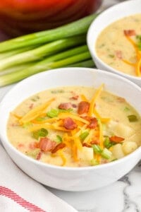 bowl of creamy potato soup with bacon topped with cheese, bacon, and scallions - 20