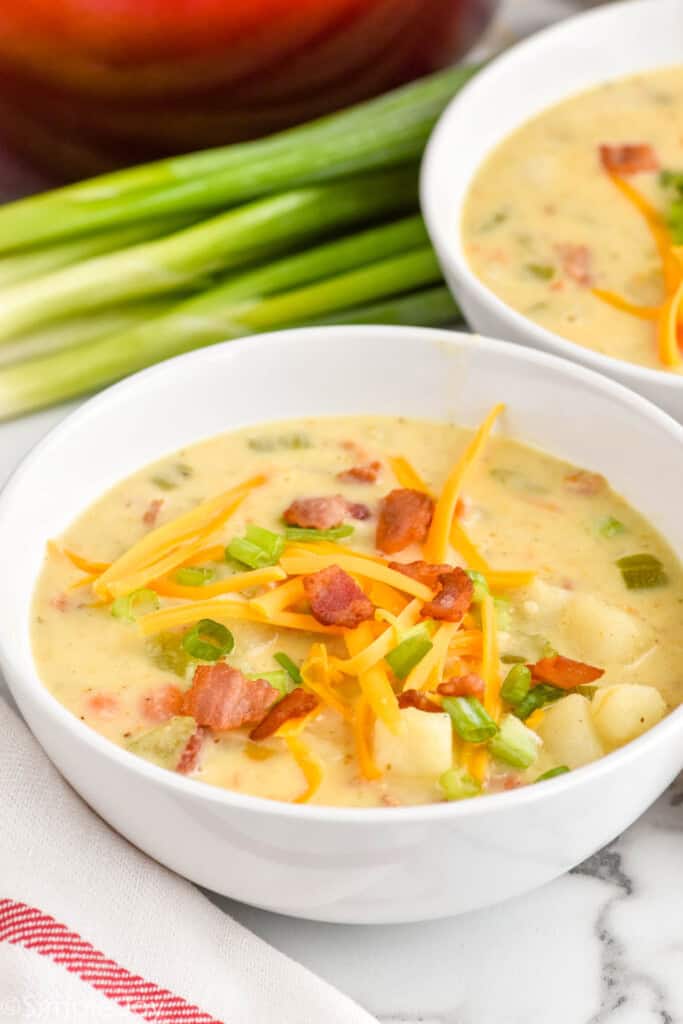 bowl of creamy potato soup with bacon topped with cheese, bacon, and scallions - 11