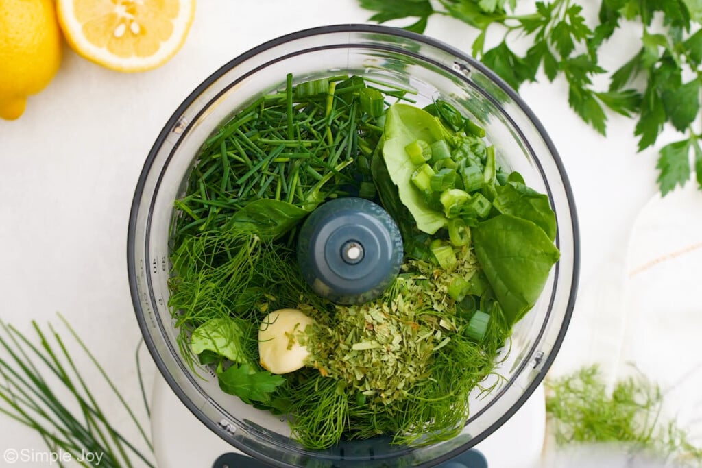 overhead of herbs in a food processor to make green goddess dressing