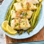 Pinterest graphic for Air Fryer Cod recipe. Image shows cod, asparagus, and lemon slices on a platter for Air Fryer Cod recipe, forks beside. Text says, "Air Fryer Cod simplejoy.com"