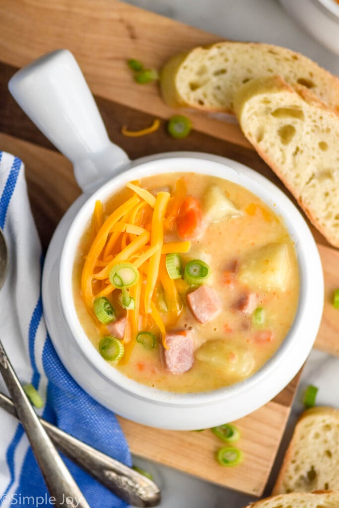Overhead photo of a bowl of Ham and Potato Soup with bread beside.