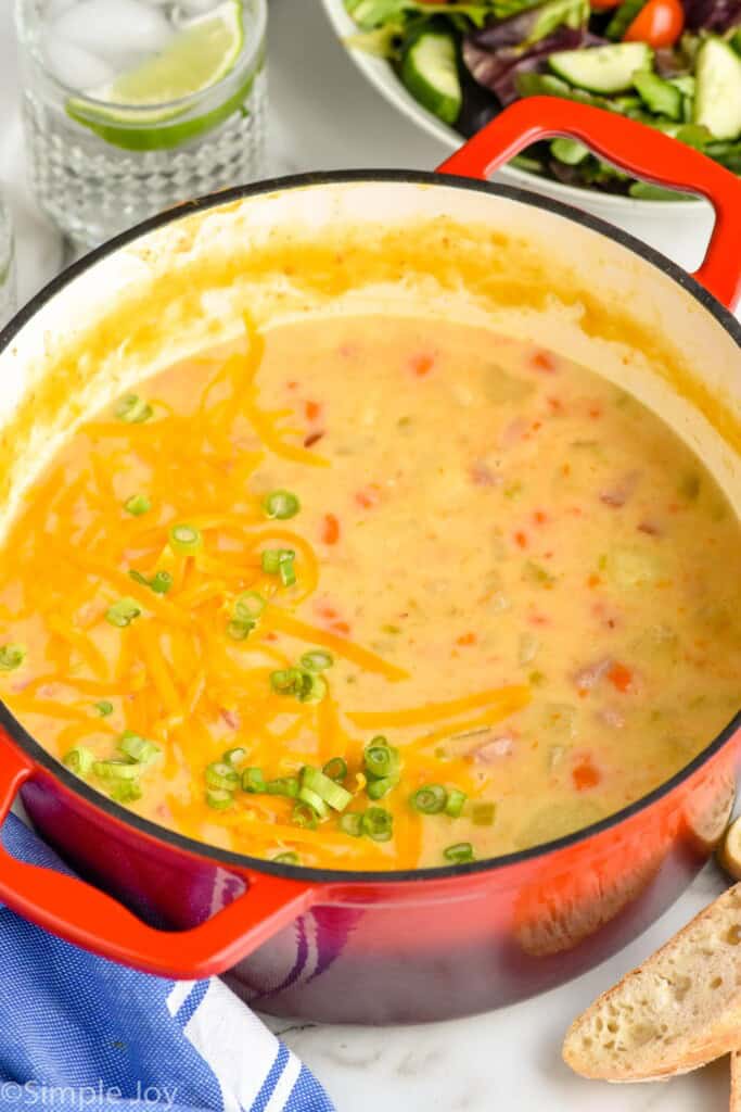 Pot of Ham and Potato Soup with salad, bread, and drink beside