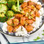 Pinterest graphic for Sesame Chicken recipe. Image shows Sesame Chicken with rice and broccoli. Text says, "Sesame Chicken simplejoy.com"