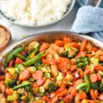 Pinterest graphic for Vegetable Stir Fry recipe. Text says, "the best Vegetable Stir Fry simplejoy.com." Image shows a skillet of Vegetable Stir Fry with a bowl of rice beside.