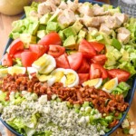 Cobb Salad with dressing and tomatoes beside