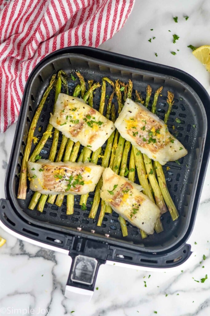 Overhead view of cod and asparagus in air fryer basket for Air Fryer Cod recipe