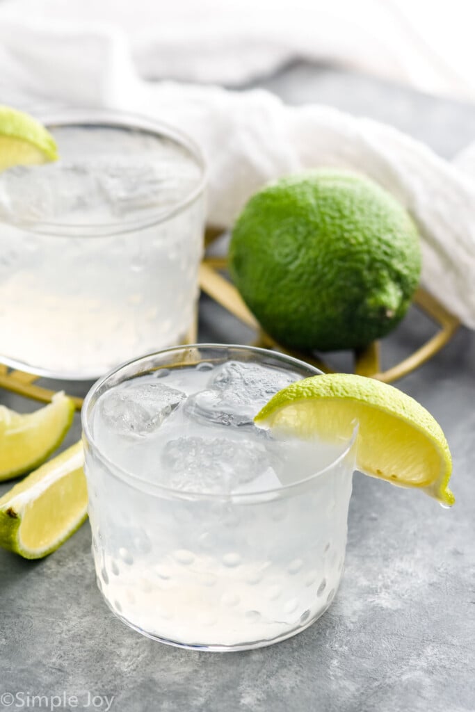 Vodka Gimlet garnished with lime wedge. Lime and lime wedges beside.