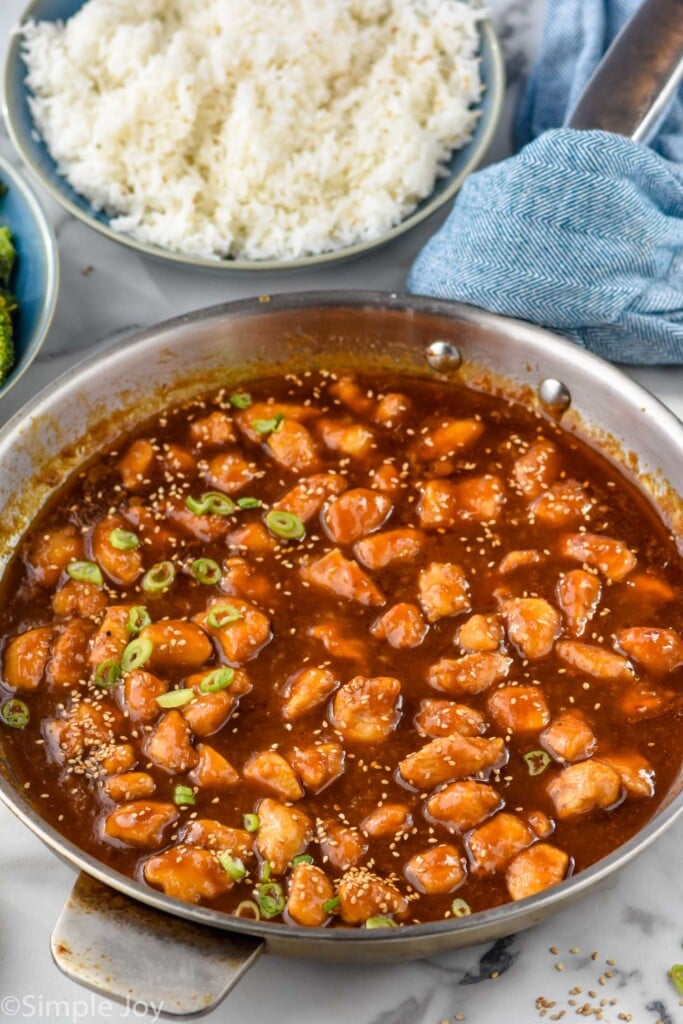 Skillet of Sesame Chicken with bowl of rice beside