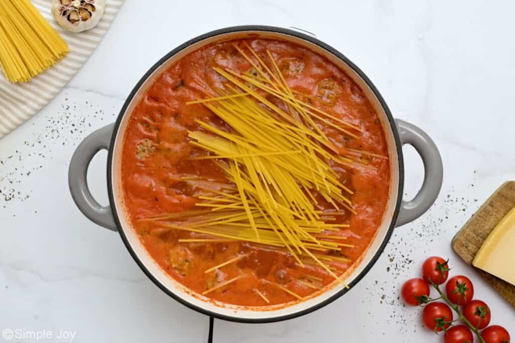 uncooked spaghetti added to a pot to make meatball soup