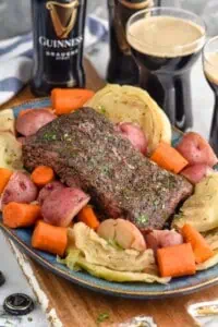 Instant Pot Corned Beef on a platter with cabbage, carrots, and potatoes. Guinness beers beside. - 7