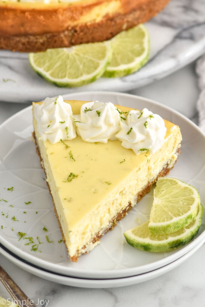 Slice of key lime cheesecake on a plate with lime wedges sitting beside.