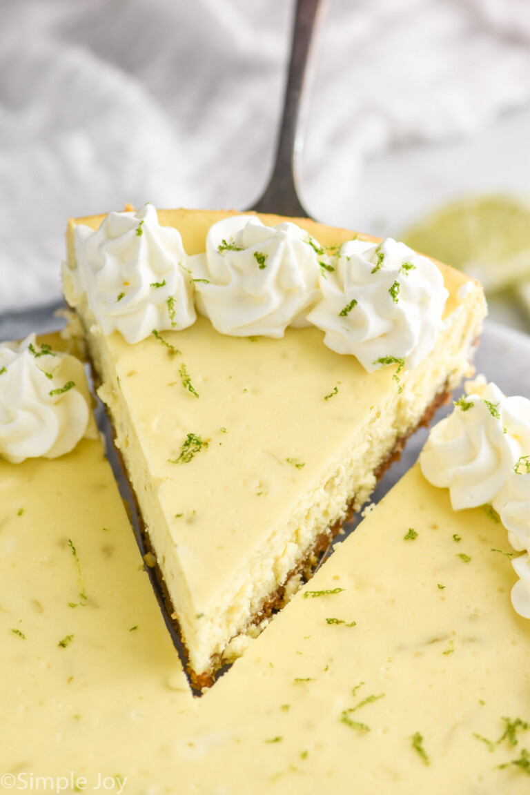 serving spatula lifting a slice of key lime pie cheesecake out of the cheesecake.