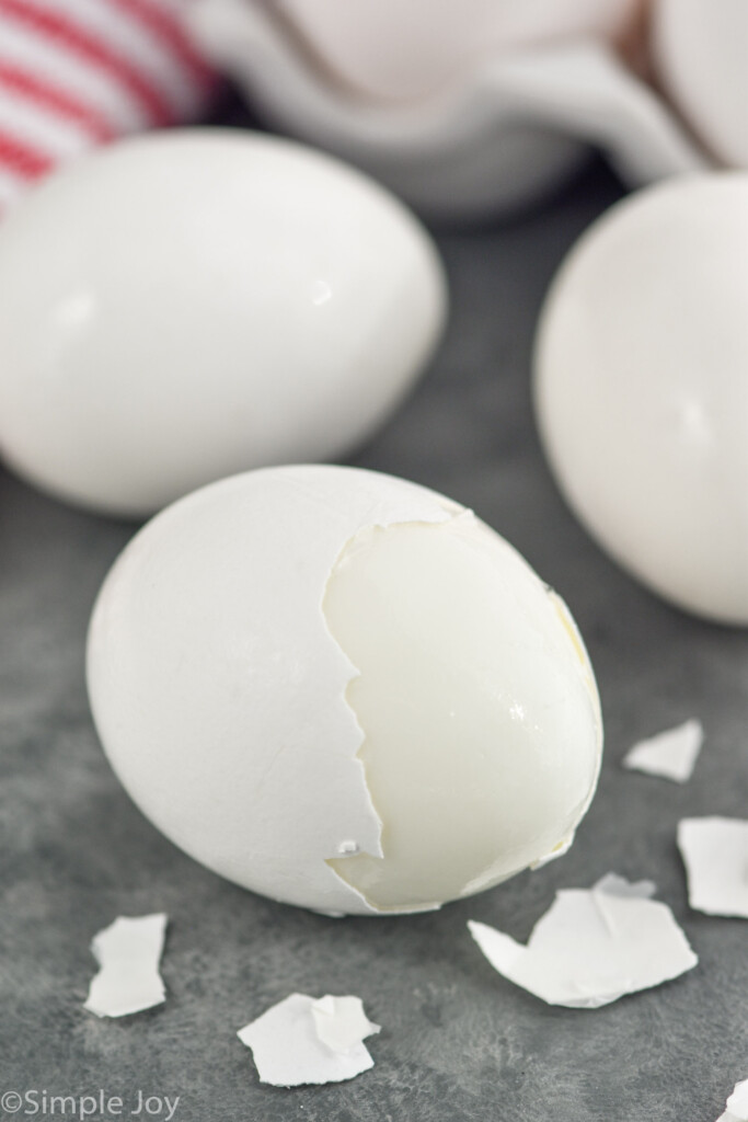 Hard boiled eggs with shell partially peeled off of front egg