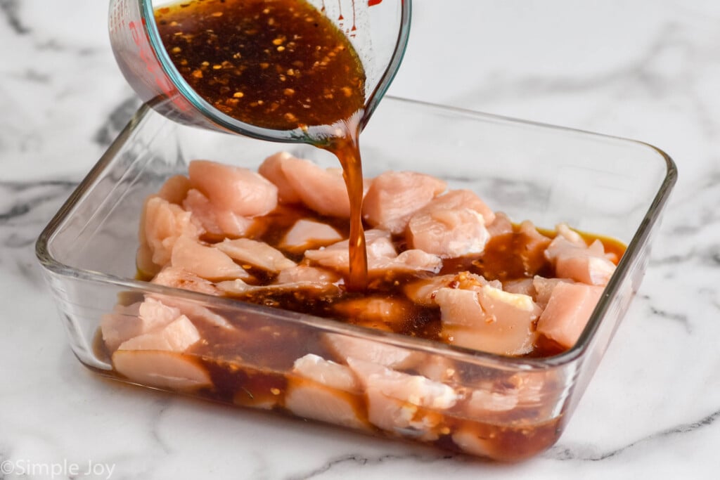 Pieces of raw chicken in container with marinade for Sesame Chicken recipe