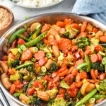 Skillet of Vegetable Stir Fry with bowl of rice beside