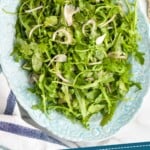 Pinterest graphic for Arugula Salad recipe. Image shows overhead view of Arugula Salad. Text says, "simple delicious Arugula Salad simplejoy.com"