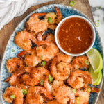 Pinterest graphic for Coconut Shrimp recipe. Text says, "the best Coconut Shrimp simplejoy.com." Image is overhead view of platter of Coconut Shrimp with chili sauce.