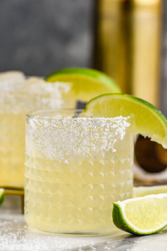 Side view of Margarita with salted rim and lime wedges