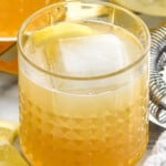 Tumbler of Gold Rush Cocktail with lemon slice and ice