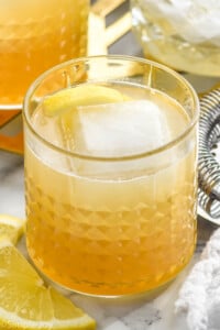 Tumbler of Gold Rush Cocktail with lemon slice and ice