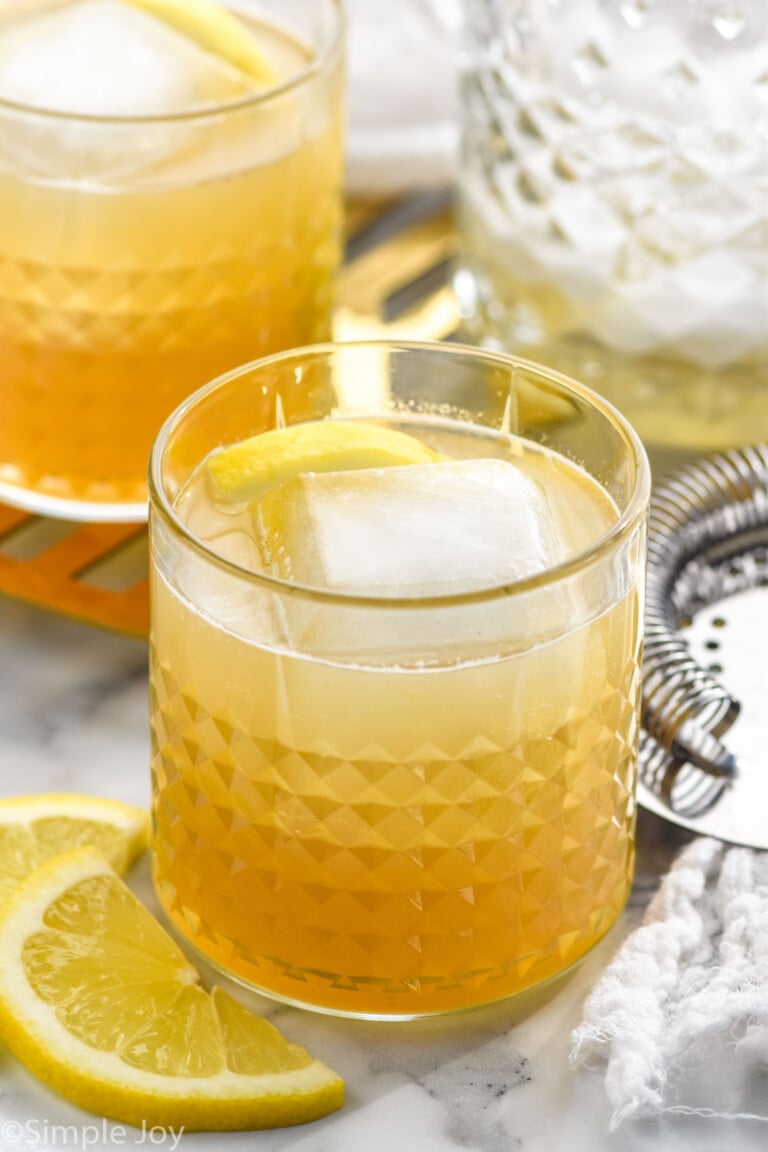 Tumbler of Gold Rush Cocktail with ice and lemon slices