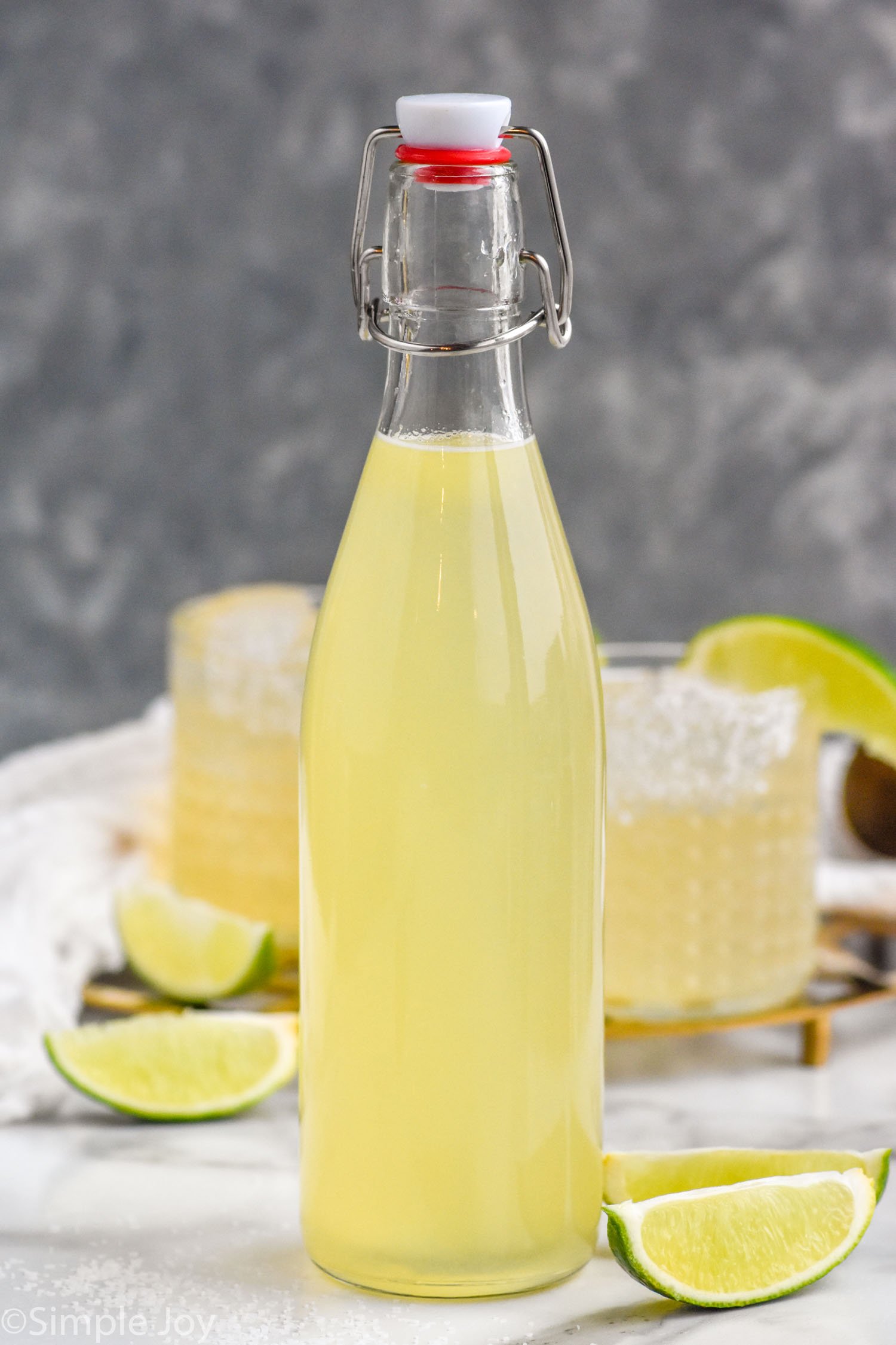 Bottle of Margarita Mix with lime slices beside
