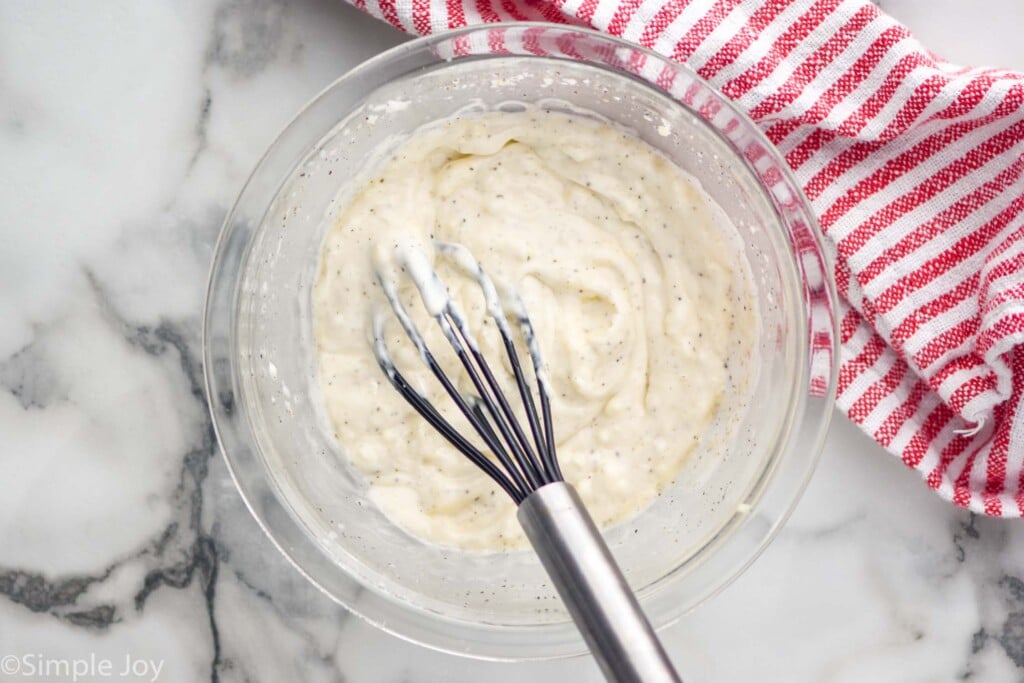 Overhead view of a mixing bowl of Garlic Aioli with whisk