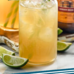 Pinterest graphic for Dark and Stormy cocktail. Image shows two glasses of dark and stormy with lime wedges and bottle of ginger beer in background. Text says "the dark and stormy simplejoy.com"
