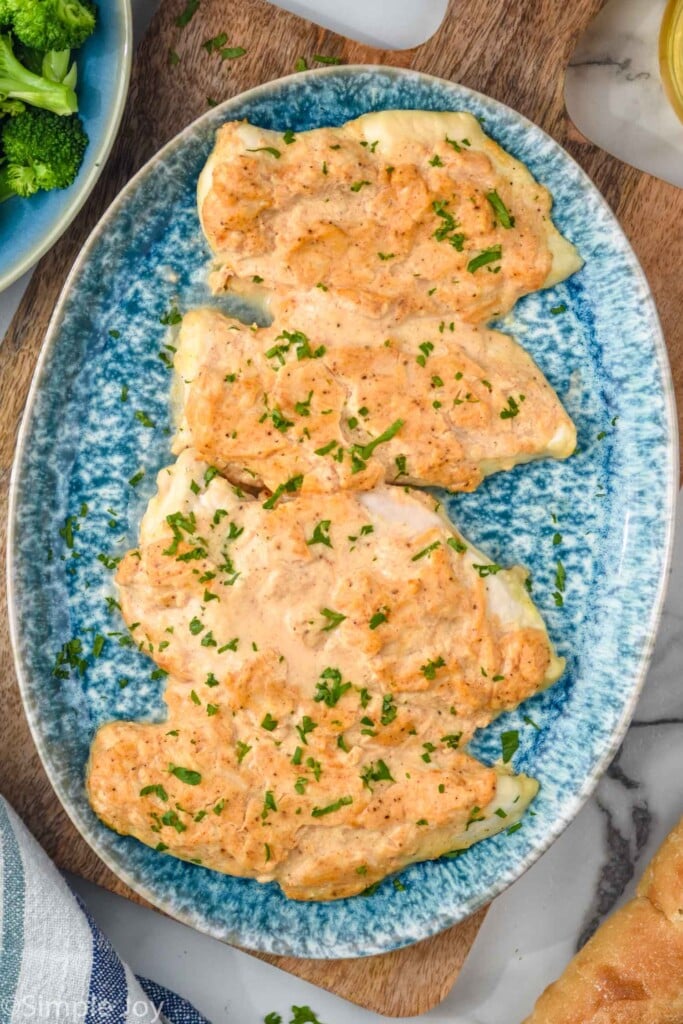 Overhead view of Melt In Your Mouth Chicken on a platter with broccoli and bread beside